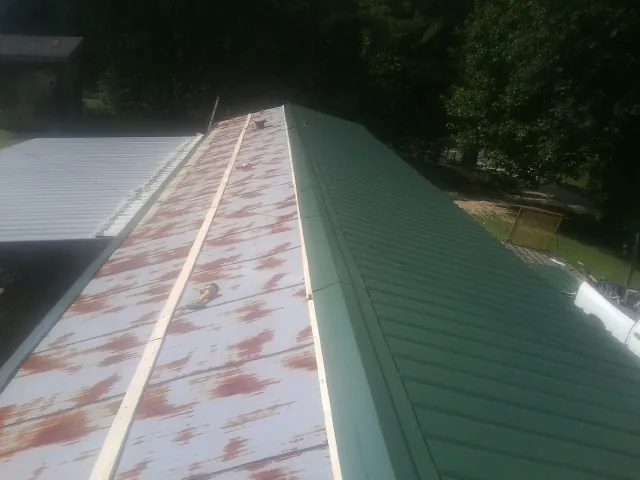 Old rusted panels beside newly installed green metal roofing — Wind Damage Roof Repair by Roofing Brothers in Mountain Dale