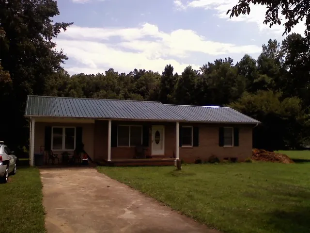 Dark green metal roof on a brick ranch with a covered porch in Mountain Dale
