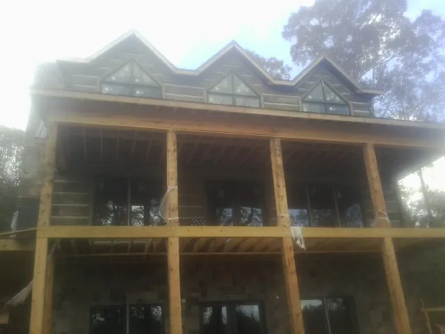 Dormers and porch framing on a large log home under construction — Roof Coating work by our crew in Mountain Dale