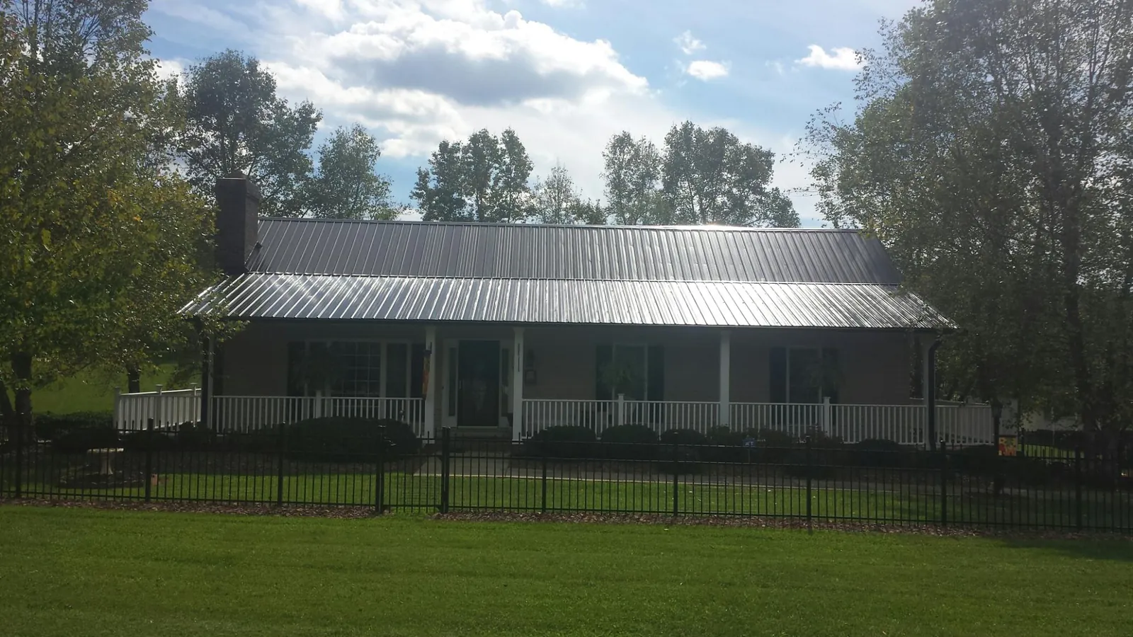 Gray metal roof on a brick ranch with a full width front porch — Gutter Guard Installation work by our crew in Mountain Dale