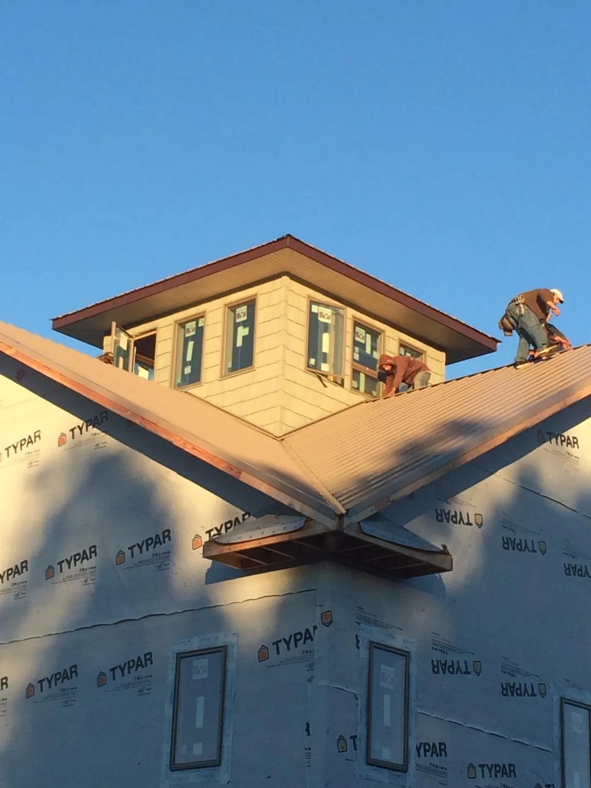 Roofers working around a rooftop cupola on a new metal roof at sunset — Roof Waterproofing in Mountain Dale by Roofing Brothers